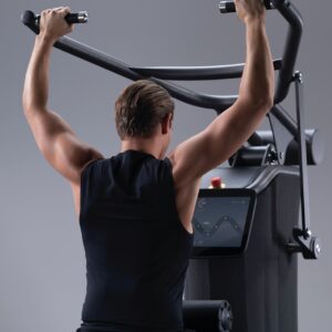 Een foto van een man die een apparaat van Matrix binnen Vita Fortis gebruikt. Op het apparaat worden de EGYM periodisering van de oefeningen gevisualiseerd. Je ziet de man van achter.