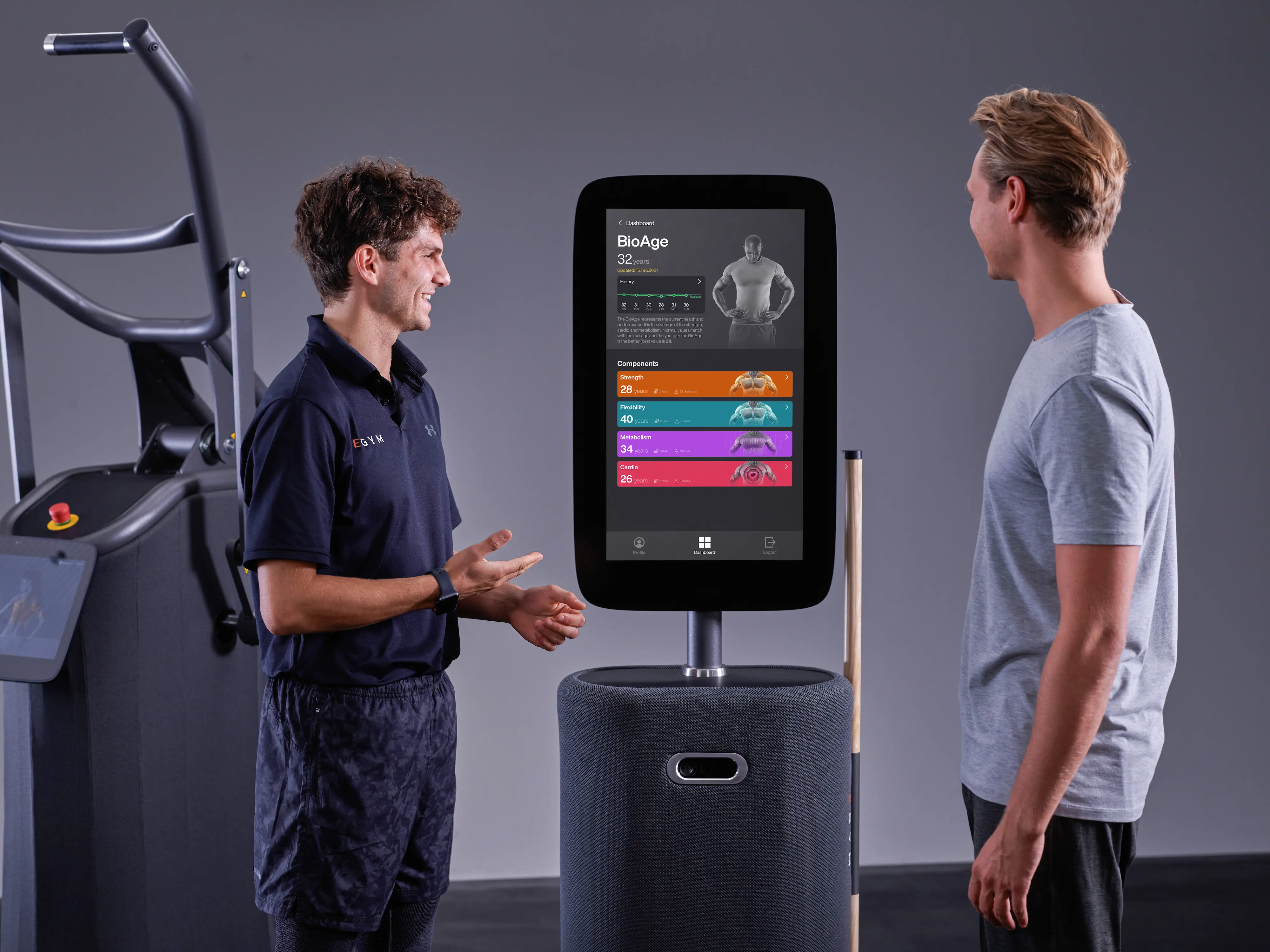 Een foto van een twee mannen die de EGYM FitnessHub gebruiken. Op het apparaat worden de EGYM pijlers en de voortgang gevisualiseerd. Je ziet de mannen van achter.