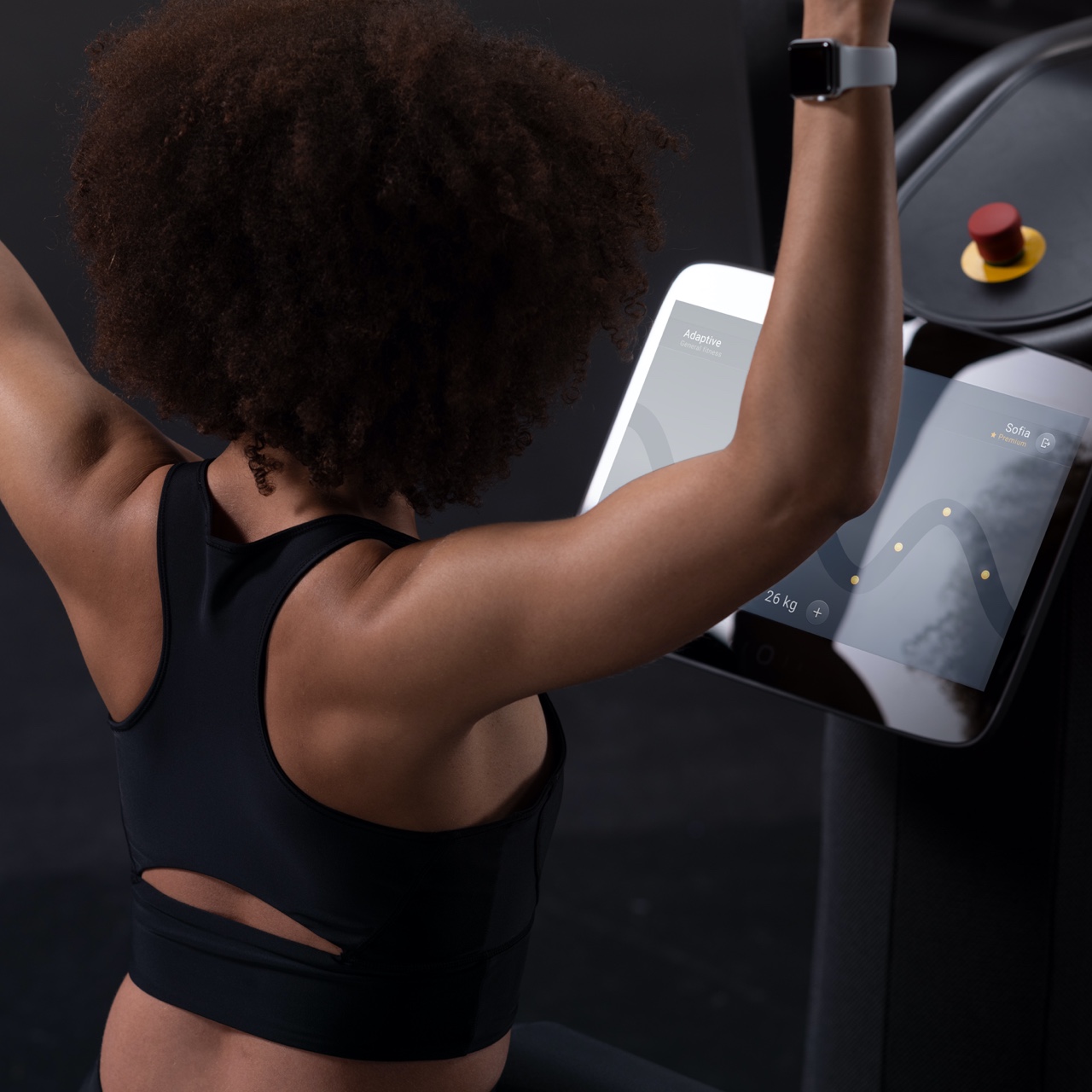 Een foto van een getinte vrouw die een apparaat van Matrix binnen Vita Fortis gebruikt. Op het apparaat worden de EGYM periodisering van de oefeningen gevisualiseerd. Je ziet de vrouw van schuin boven, rechtsachter.