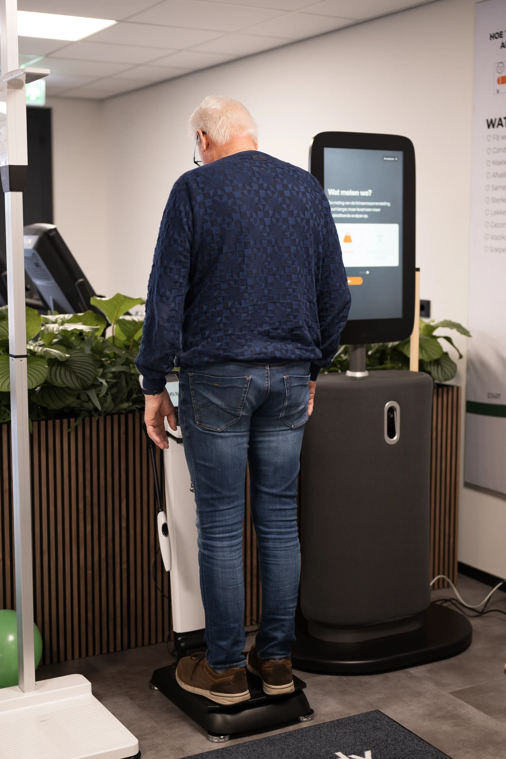 Een oudere man is in vitaliteitsstudio Vita Fortis bezig met zijn vitaliteitscheck op de weegschaal.